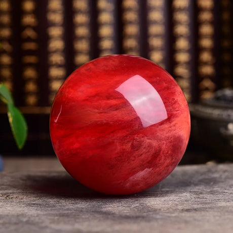 Red marble-like sphere with a pink center on a wooden surface
