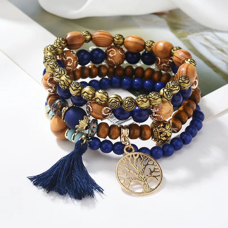 Stack of beaded bracelets with a tassel and tree-of-life charm on a white surface