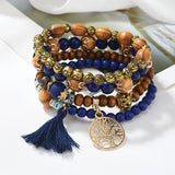 Stack of beaded bracelets with a tassel and tree-of-life charm on a white surface