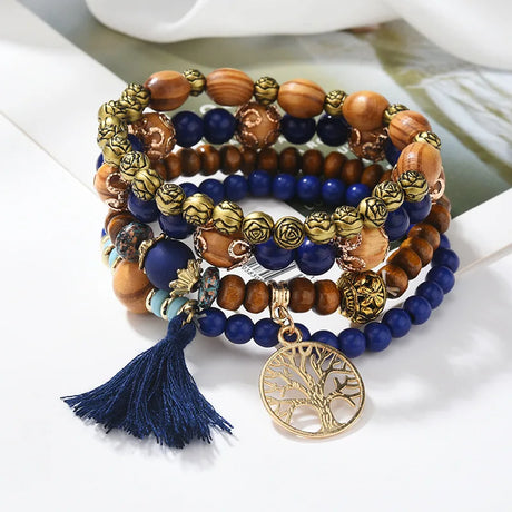 Stack of beaded bracelets with a tassel and tree-of-life charm on a white surface