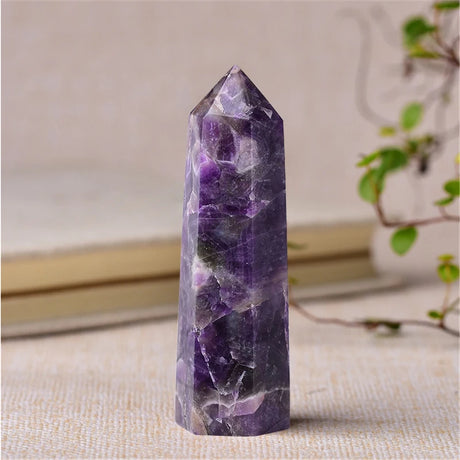 Amethyst crystal tower on a textured surface with a neutral background