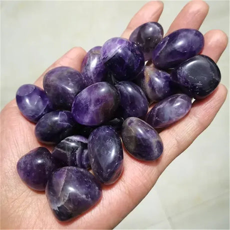Hand holding a collection of purple stones against a neutral background
