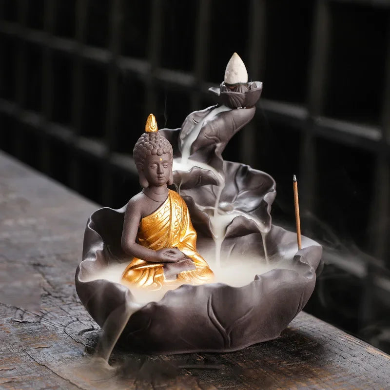 Incense burner shaped like a Buddha figure with smoke rising, on a dark background.