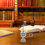 Silver decorative censer on a wooden desk with books in the background