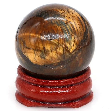 Tiger's eye crystal ball on a red stand against a white background