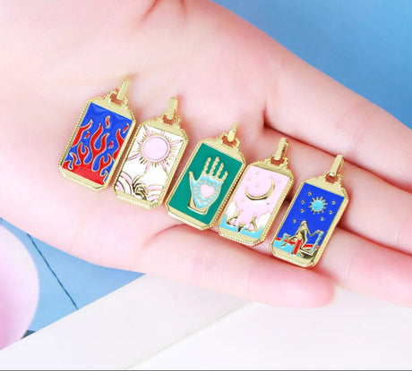 Five colorful tarot card pendants held in a hand against a blue background