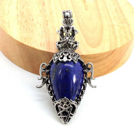 Decorative pendant with blue stone and silver detailing on a wooden background