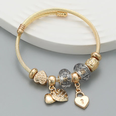 Gold bracelet with various charms on a light gray background