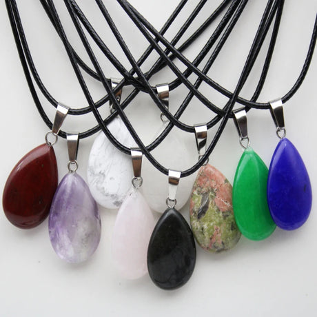 Necklaces with colorful teardrop pendants on black cords against a white background