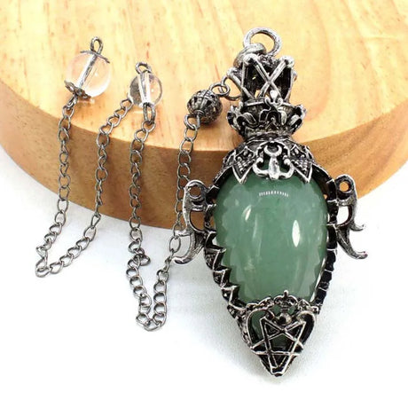 Green teardrop pendant with silver chain on a wooden surface