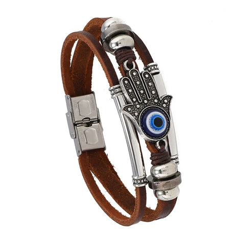 Bracelet with brown leather strap, silver metal elements, and blue evil eye charm on a white background