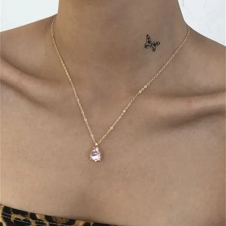 Gold necklace with a teardrop pendant on a person's neck