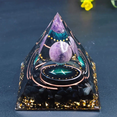 Decorative pyramid with purple crystal ball on a dark background