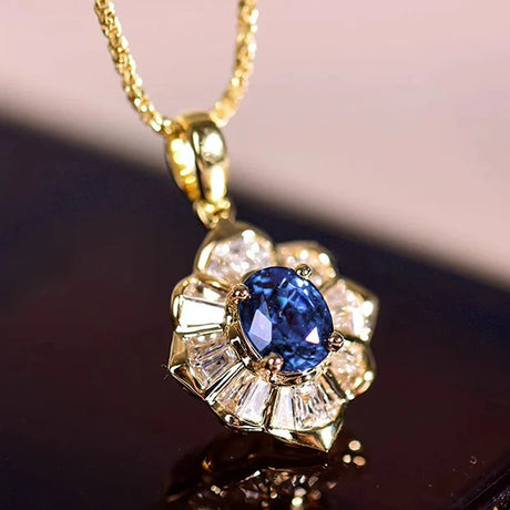 Gold pendant with a blue gemstone and diamonds on a reflective surface