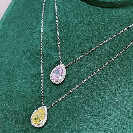Two teardrop-shaped gemstone necklaces on a green fabric background