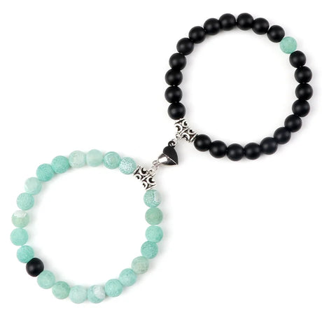 Two beaded bracelets, one with black beads and the other with green beads, on a white background.