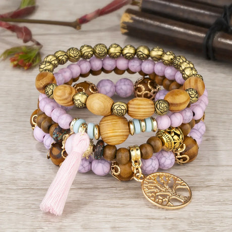 Set of beaded bracelets with a tassel and tree-of-life charm on a wooden surface.