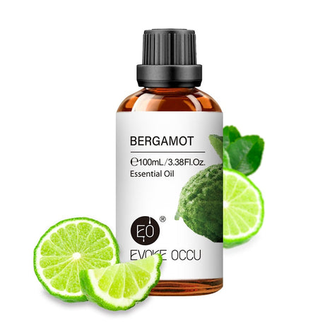 Bottle of Bergamot essential oil by Evoke Occu with lime slices on a white background
