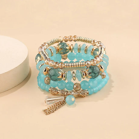 Stack of turquoise beaded bracelets with gold accents on a beige background