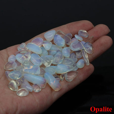 Hand holding a collection of opalite stones with a dark background