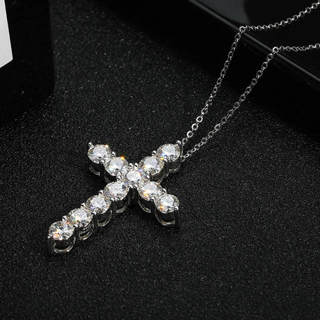 Silver cross necklace with clear stones on a black background