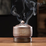 Bronze incense burner with smoke on a wooden surface