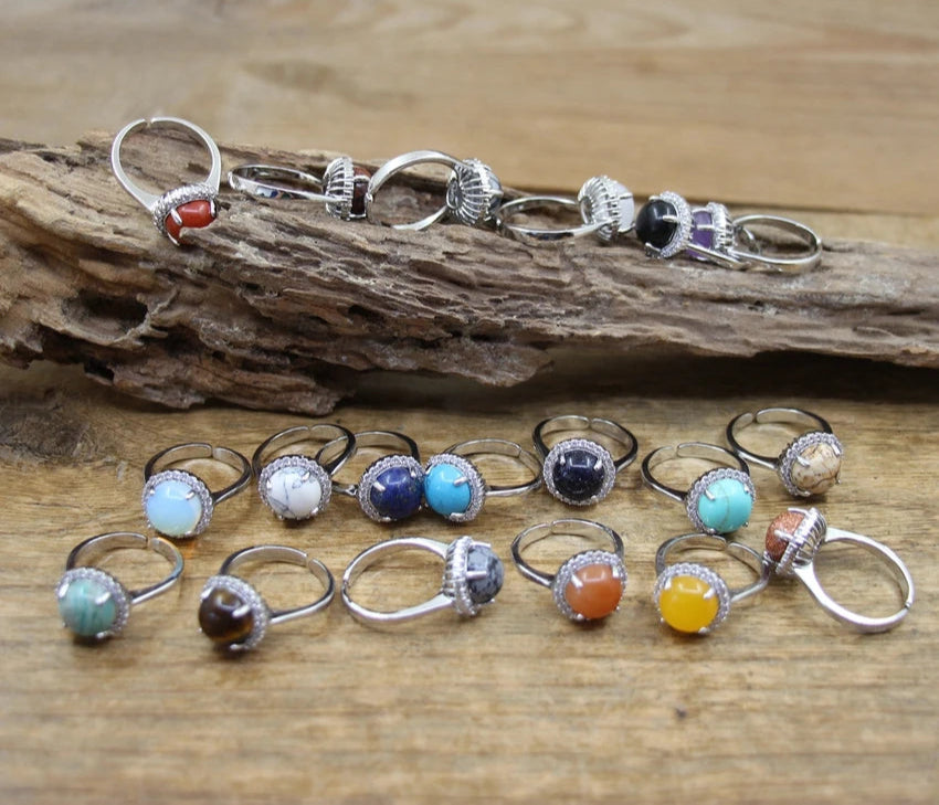 Set of silver rings with colorful gemstones on a wooden surface