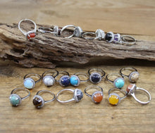 Set of silver rings with colorful gemstones on a wooden surface