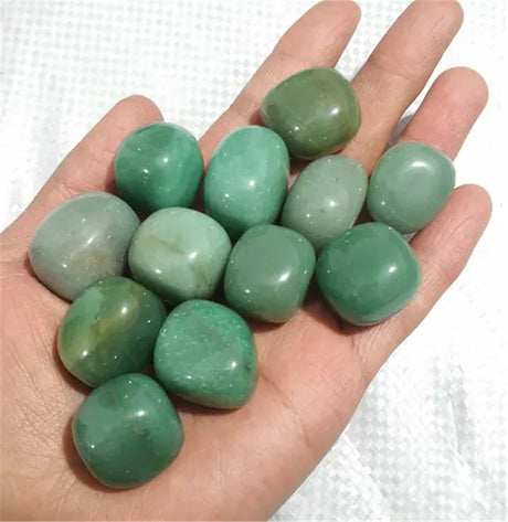 Hand holding green stones against a white background