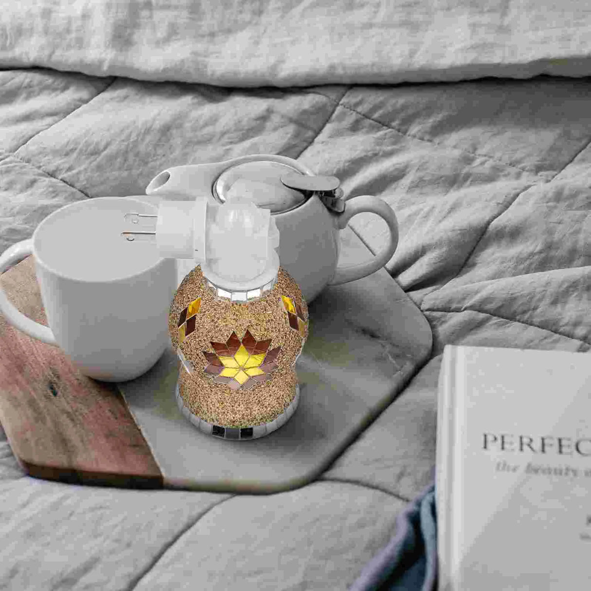 Tea set with a decorative teapot and mug on a wooden board, placed on a textured surface.