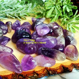 Amethyst crystals on a wooden surface with greenery in the background