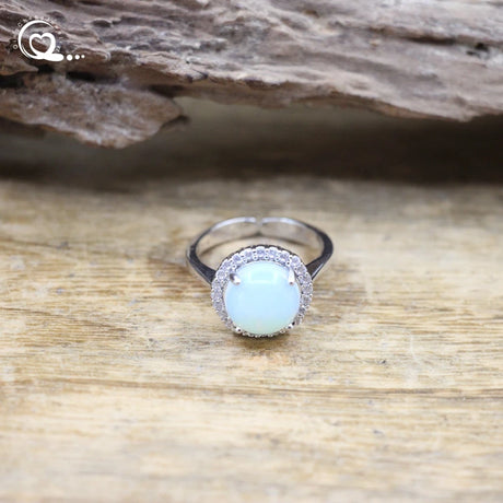 Silver ring with a light blue gemstone on a wooden surface