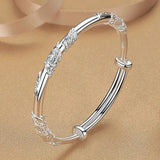 Silver bracelet with floral designs on a beige background