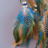 Decorative feather ornament with blue, green, and beige feathers on a plain background