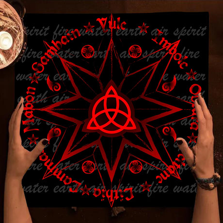 Person holding a black board with red geometric design and symbols on a dark background