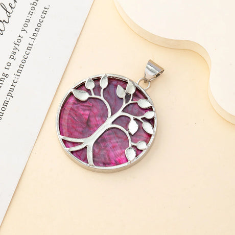 Silver tree of life pendant with pink center on a beige stand.