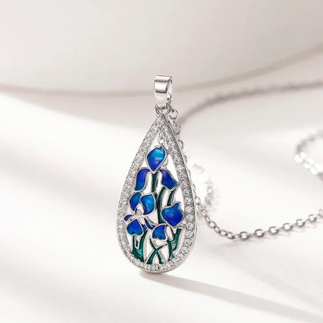 Teardrop-shaped pendant with blue floral design on a white background