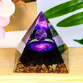 Pyramid-shaped decorative item with purple and gold elements on a wooden surface.