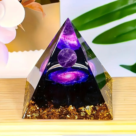 Pyramid-shaped decorative item with purple and gold elements on a wooden surface.
