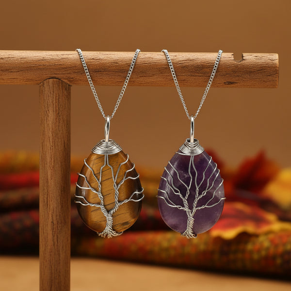 Two tree-shaped stone pendants, one brown and one purple, on silver chains against a white background.