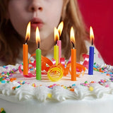 Child blowing out colorful candles on a birthday cake with a red background