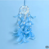 Blue dreamcatcher with feathers and lights on a light blue background