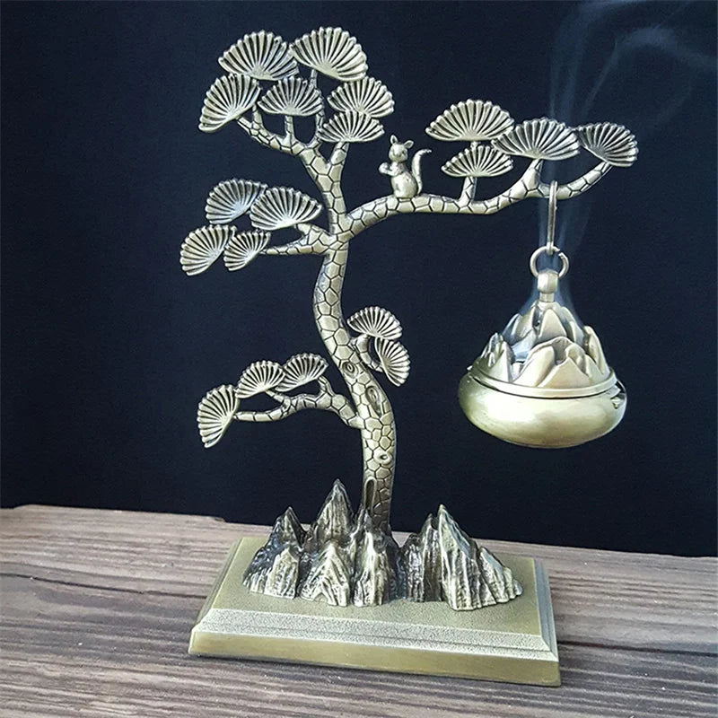 Decorative metal incense burner shaped like a tree with mountains on a dark background