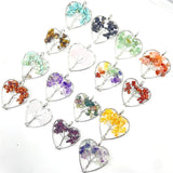 Heart-shaped pendants with embedded stones and leaves on a white background