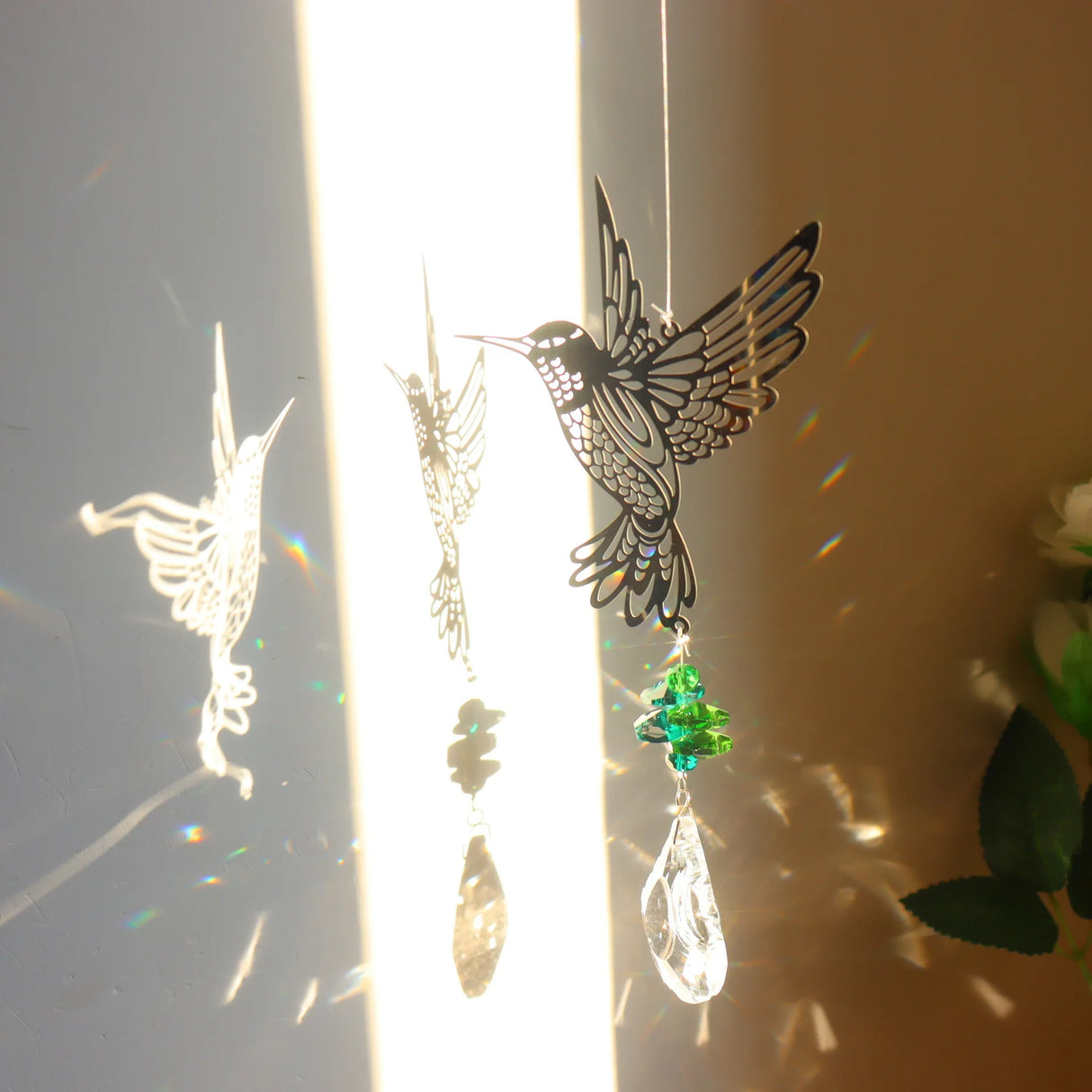 Decorative hanging ornament with a hummingbird design and rainbow beads on a light background