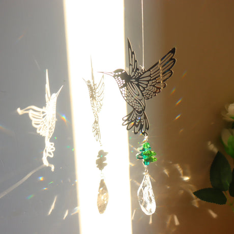 Decorative hanging ornament with a hummingbird design and rainbow beads on a light background