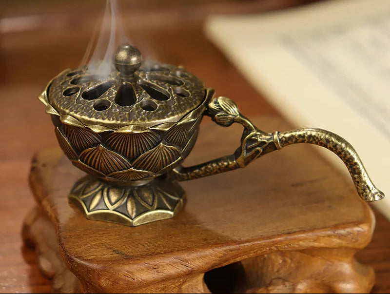 Bronze incense burner with smoke on a wooden surface