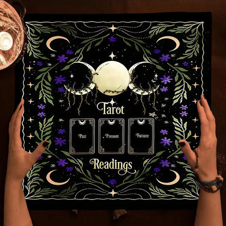 Decorative mat with tarot design held by hands, featuring moon phases and card labels.