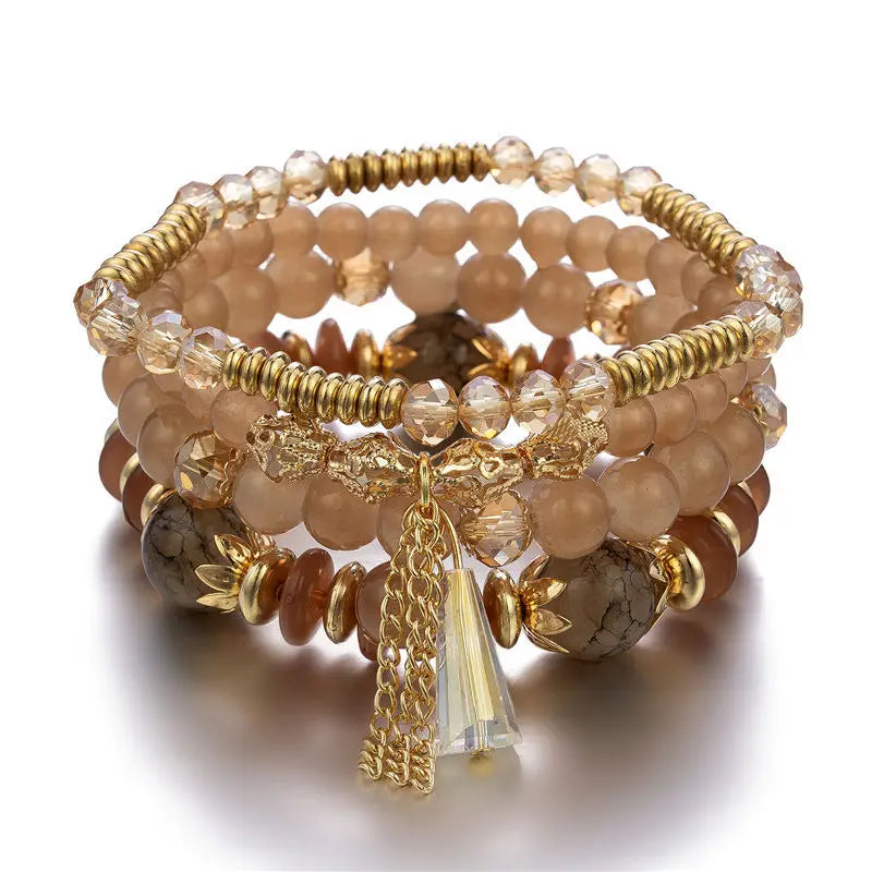 Stack of beaded bracelets with gold accents and a tassel charm on a white background