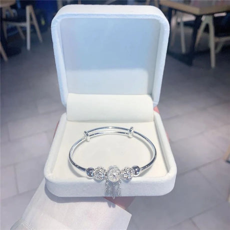 Silver bracelet with decorative elements in a white jewelry box on a blurred indoor background